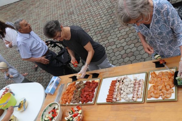 Gäste stecken sich das Fleisch auf den Grill